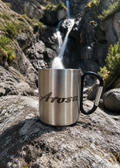Tasse mit Karabinerhacken mit Arosa Schriftzug vor Wasserfall